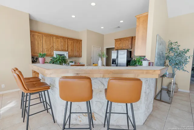 a kitchen with stainless steel appliances a dining table chairs and a refrigerator