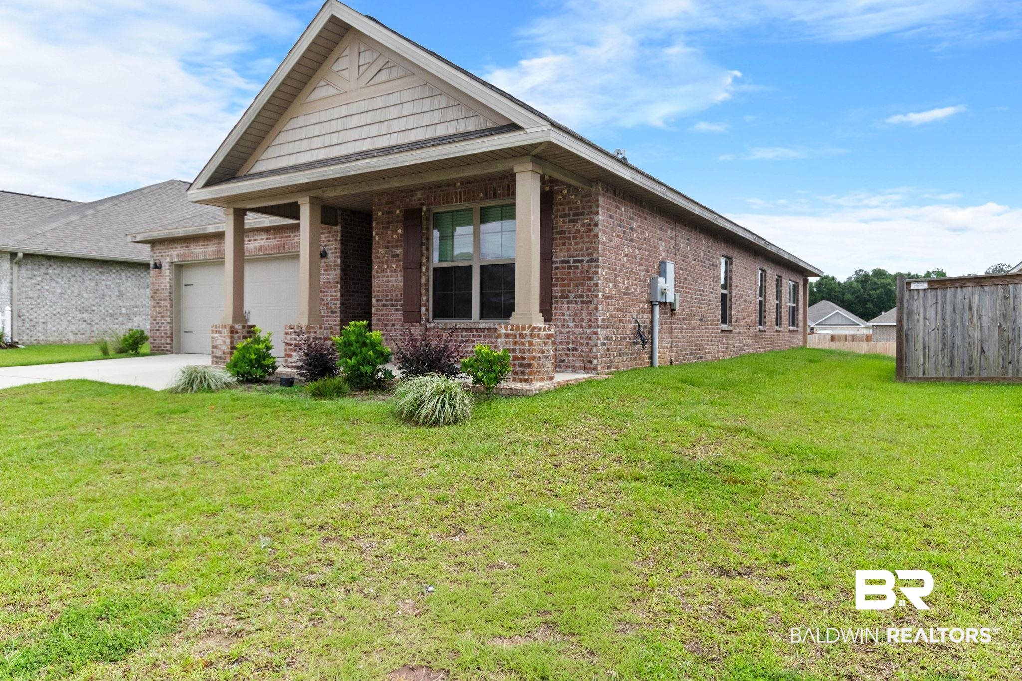 1710 Grouse Street Foley, AL 36535 - Photo 11 of 76 Brick-clad home featuring a covered front porch with column supports, a two-car garage, and a gable roof with decorative shingles