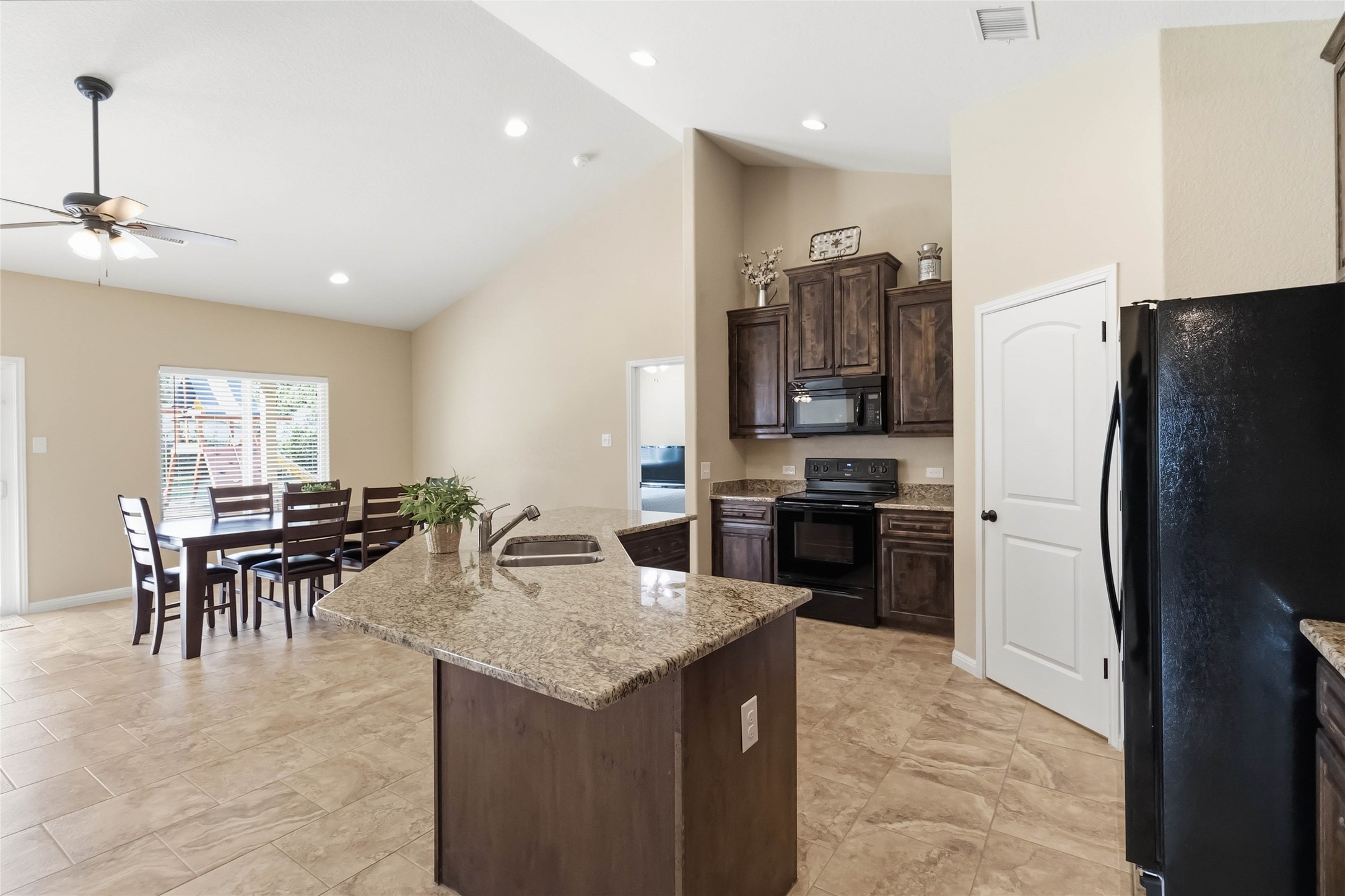 285 Hummingbird Way Martindale, TX 78655 - Photo 11 of 40 a kitchen with granite countertop kitchen island a refrigerator and a dining table