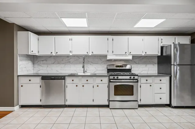 a large kitchen with stainless steel appliances granite countertop a lot of cabinets and wooden floor