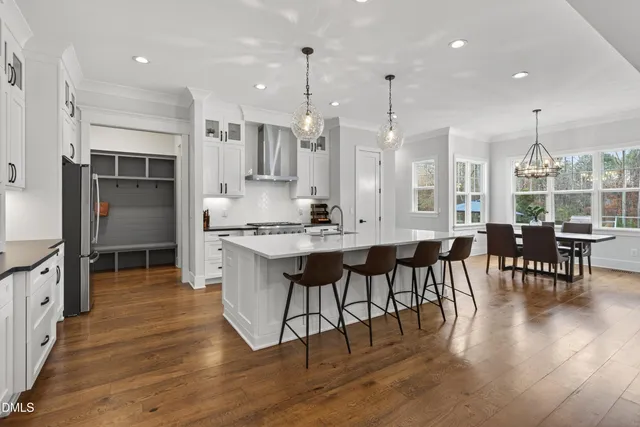 a kitchen with stainless steel appliances kitchen island granite countertop a dining table chairs and white cabinets