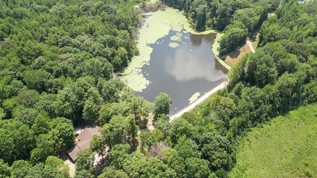 an aerial view of a house with a yard and trees all around