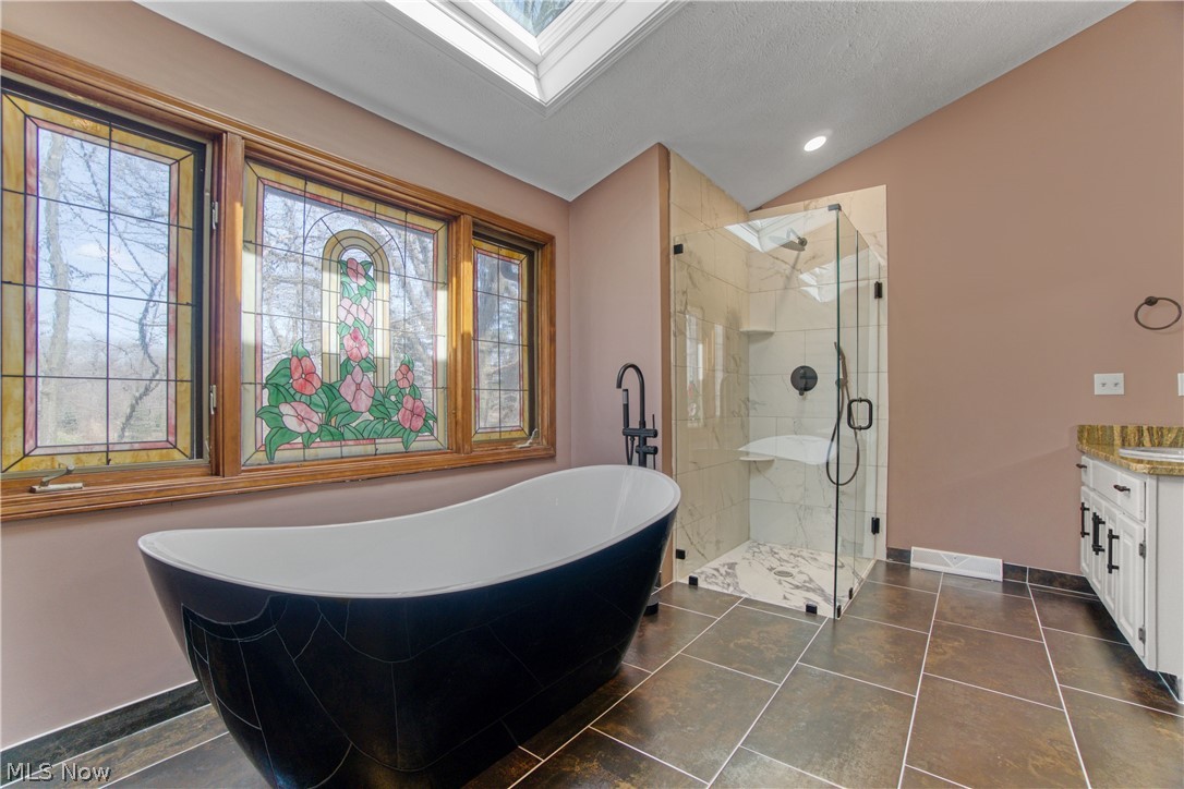 29329 Eddy Road Wickliffe, OH 44092 - Photo 23 of 50 Bathroom with tile flooring, vaulted ceiling with skylight, vanity, and a wealth of natural light