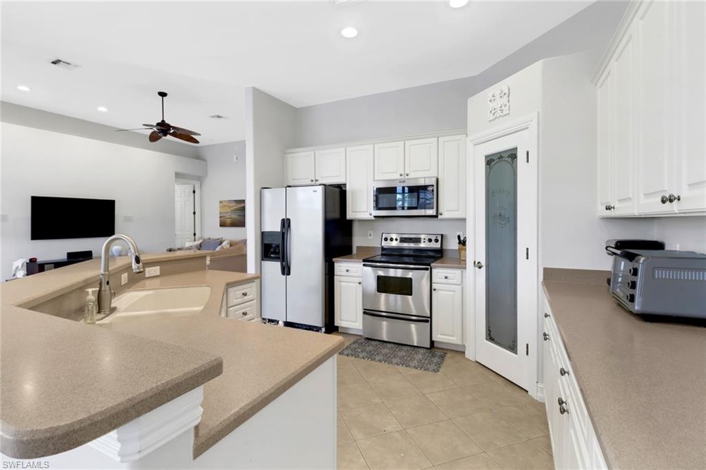 6757 Bent Grass Drive Naples, FL 34113 - Photo 10 of 27 a kitchen with stainless steel appliances a microwave sink refrigerator and cabinets