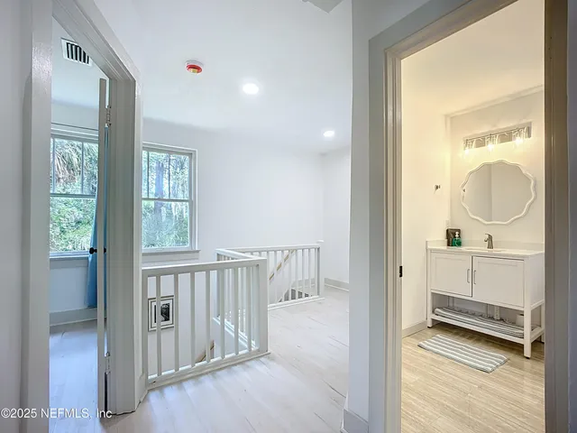 a view of a hallway and a livingroom with wooden floor a bathroom view