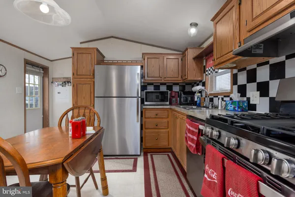 a kitchen with stainless steel appliances granite countertop a refrigerator a stove top oven a sink dishwasher and white cabinets with wooden floor