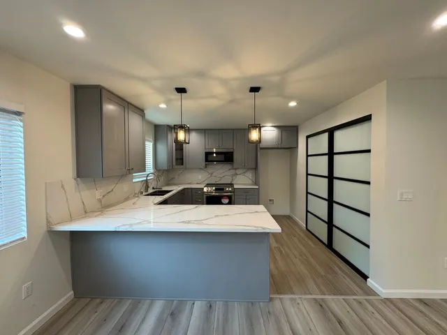 a large kitchen with a large counter top space a sink wooden floor and a large window