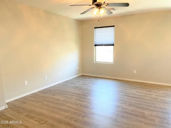 an empty room with wooden floor fan and windows