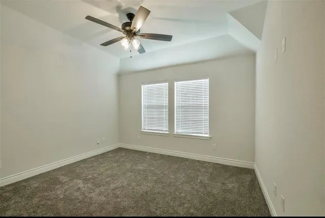 an empty room with a chandelier fan and windows