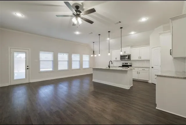 a large kitchen with cabinets wooden floor and stainless steel appliances