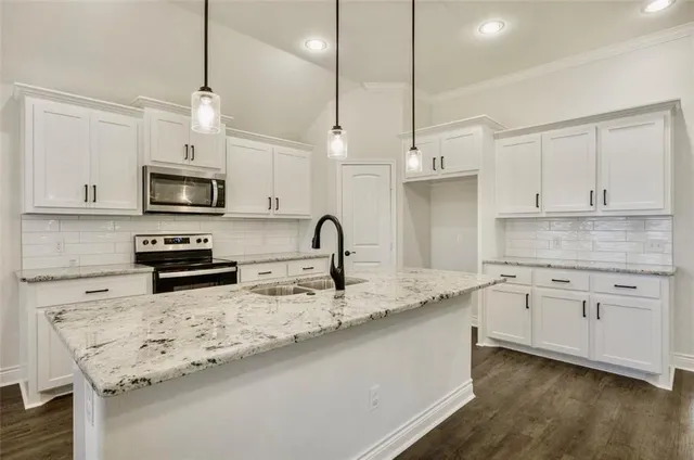a kitchen with granite countertop a sink stainless steel appliances and white cabinets