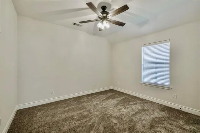 an empty room with a chandelier fan and windows