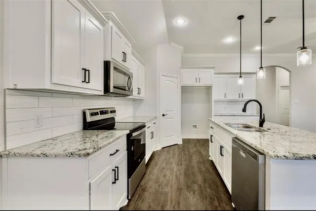 a kitchen with stainless steel appliances granite countertop a sink a stove and a refrigerator
