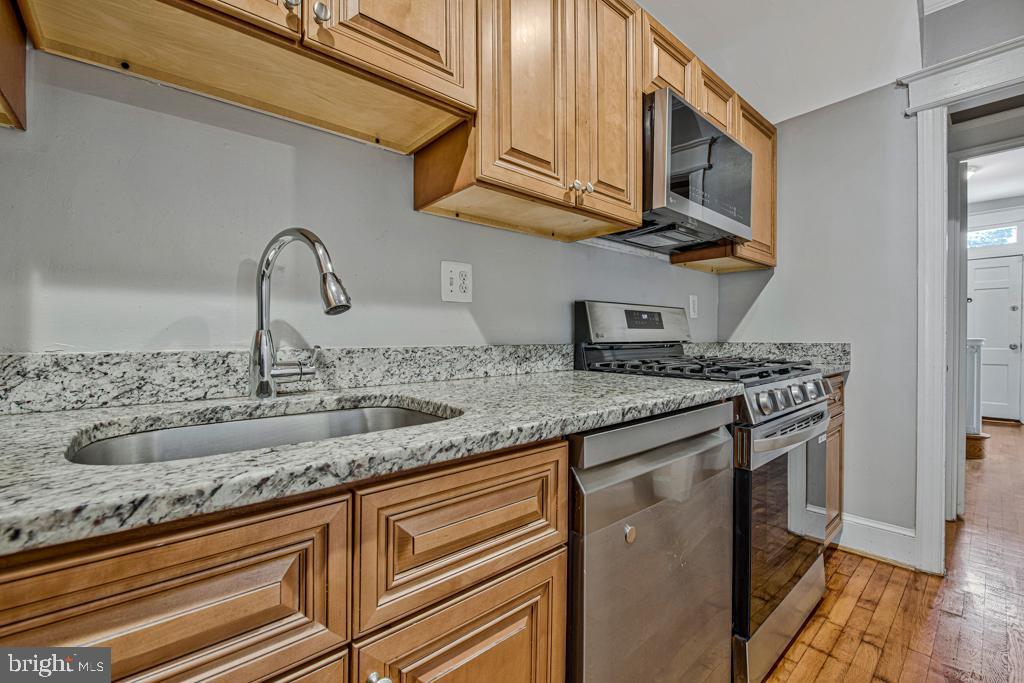 2406 37th Street Northwest Washington, DC 20007 - Photo 12 of 44 a kitchen with stainless steel appliances granite countertop a sink a stove and cabinets