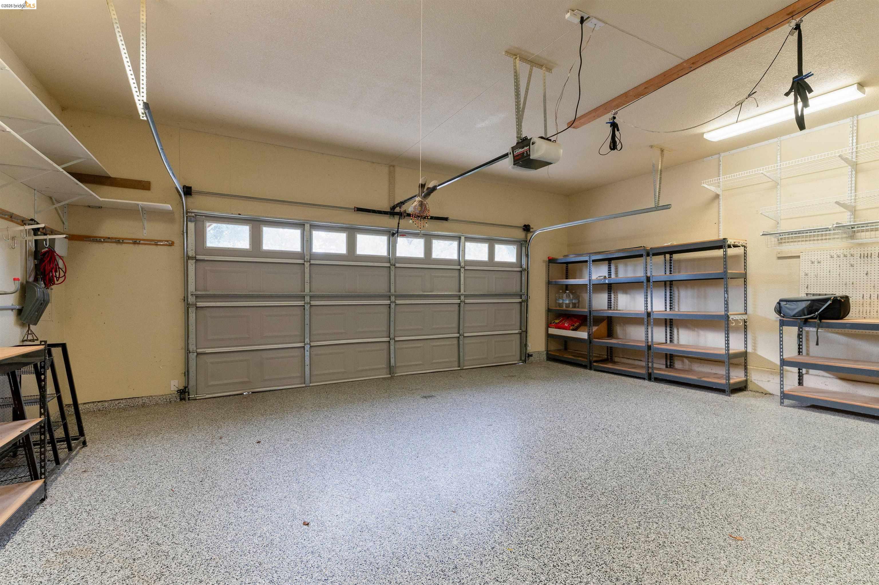 22401 Ridge Road Twain Harte, CA 95383 - Photo 31 of 56 Spacious garage featuring a finished epoxy floor, an automatic garage door with upper window panels, and ample built-in shelving for organized storage