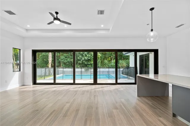 a view of an empty room with a window and wooden floor
