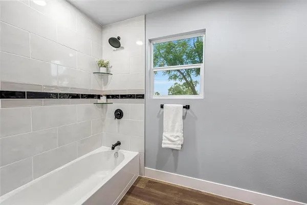 a bathroom with a tub a window and a shower