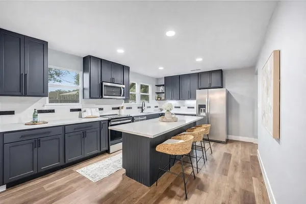 a kitchen with stainless steel appliances granite countertop a sink stove refrigerator and cabinets