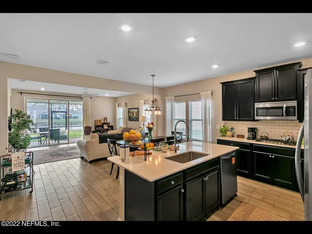 a living room with stainless steel appliances kitchen island granite countertop a sink dishwasher stove and couches with wooden floor