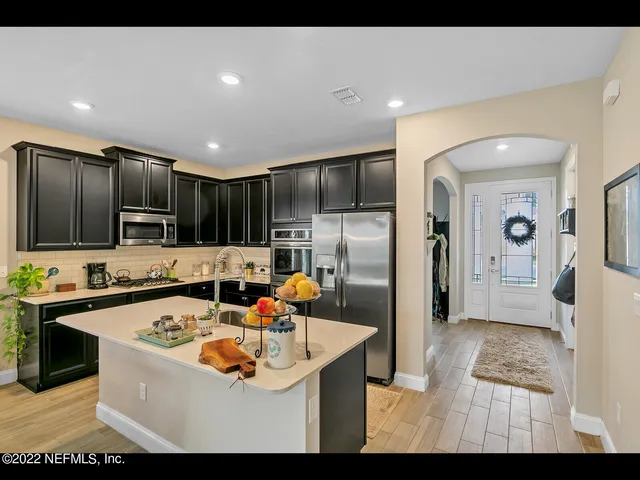 a kitchen with stainless steel appliances a sink a stove a refrigerator cabinets and a dining table