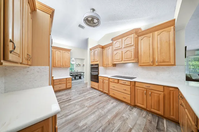 a view of a kitchen with kitchen island wooden floor and stainless steel appliances