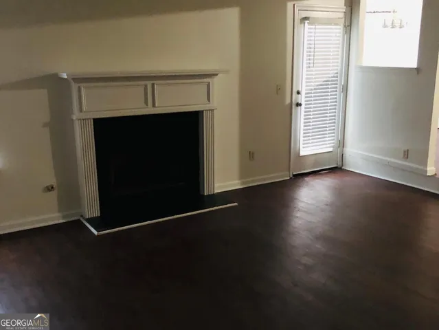 an empty room with wooden floor fireplace and windows