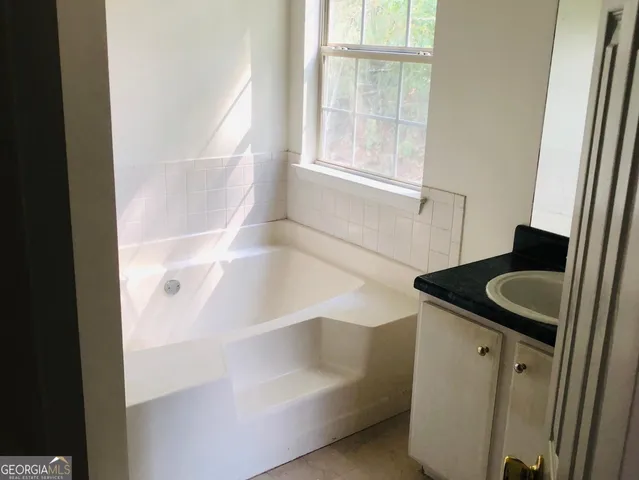 a bathroom with a tub sink and mirror