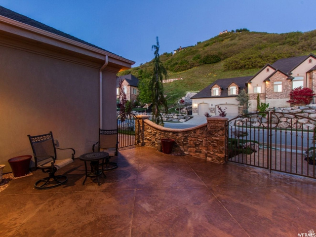 4378 Foothill Drive Bountiful, UT 84010 - Photo 43 of 46 Stained concrete patio featuring a stone-clad retaining wall and wrought iron gate
