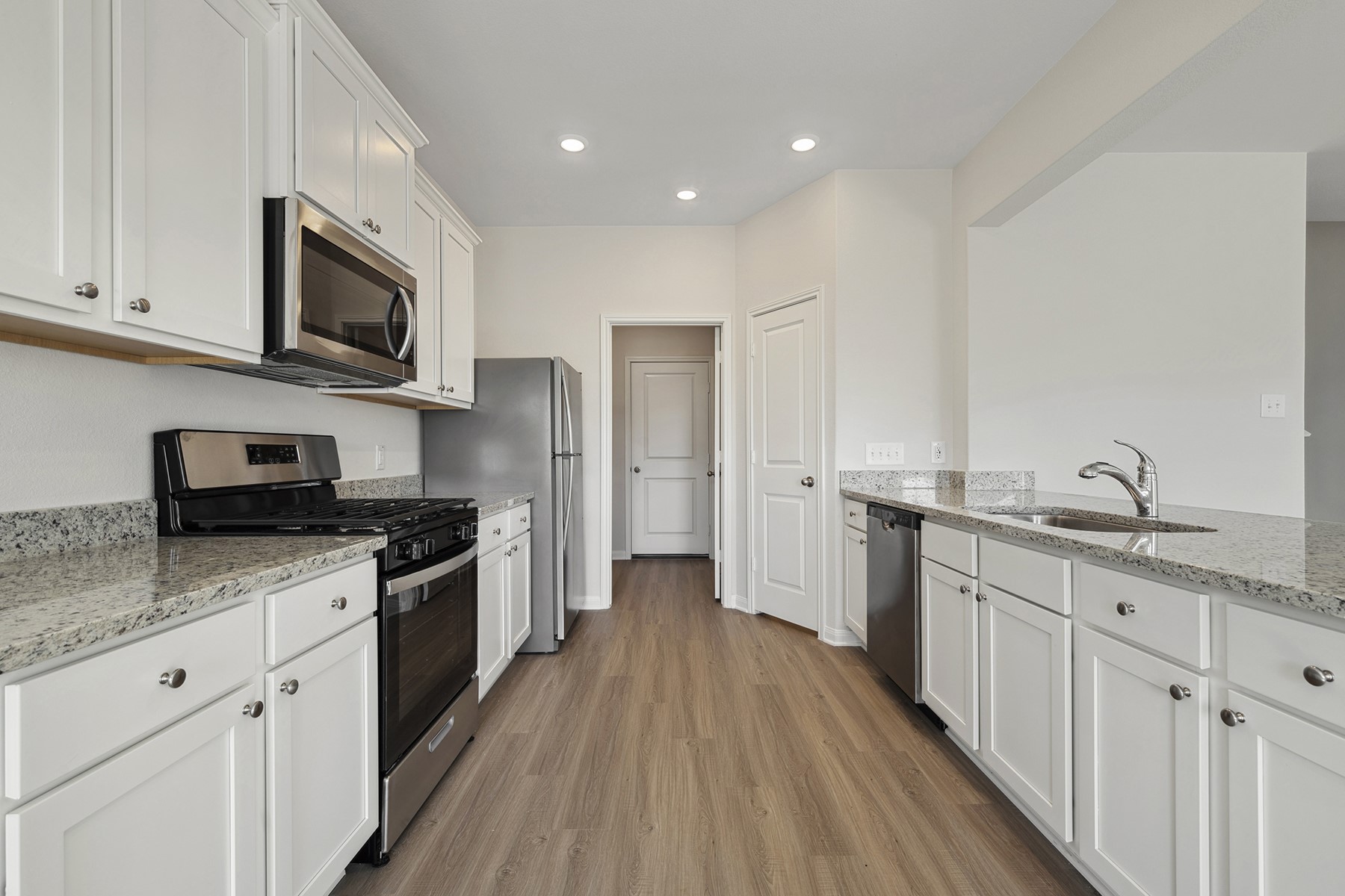 360 Kingston Way Waller, TX 77484 - Photo 6 of 21 a kitchen with stainless steel appliances granite countertop a stove top oven a sink dishwasher and a refrigerator with wooden floor
