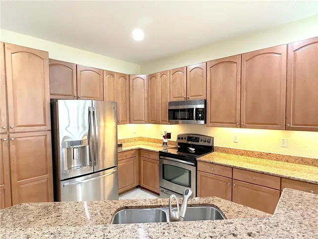 a kitchen with stainless steel appliances granite countertop a refrigerator sink and stove