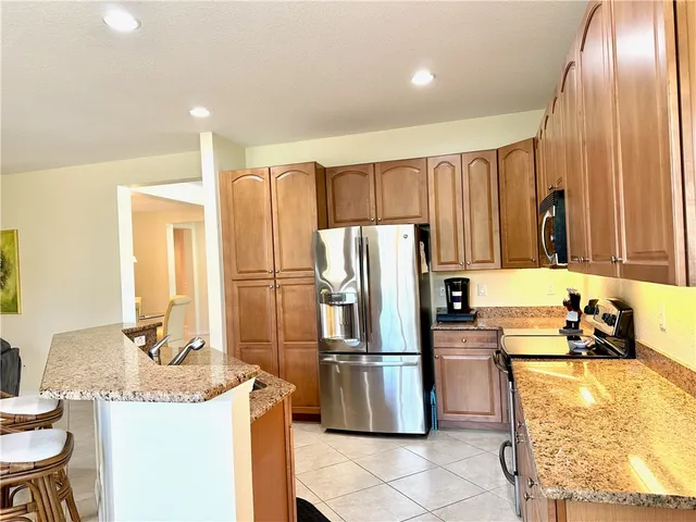 a kitchen with granite countertop a refrigerator and a stove top oven
