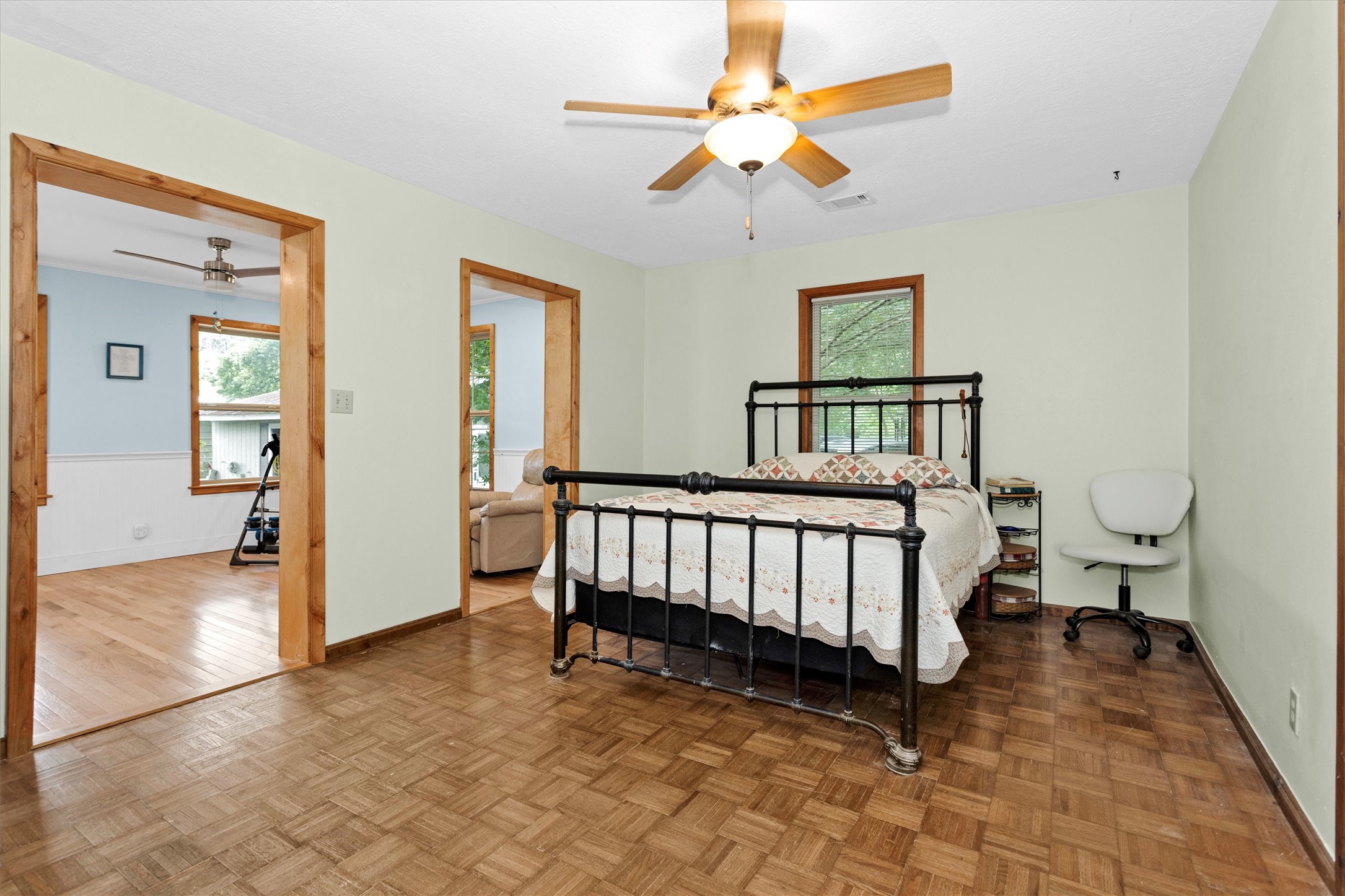 32117 Old Hempstead Road Magnolia, TX 77355 - Photo 14 of 26 Primary bedroom featuring parquet wood flooring, ceiling fan, natural wood trim, and access to an 11x16 added flex room currently used as an office. The additional space offers versatility for a home office, sitting area, nursery, workout room, or private retreat.