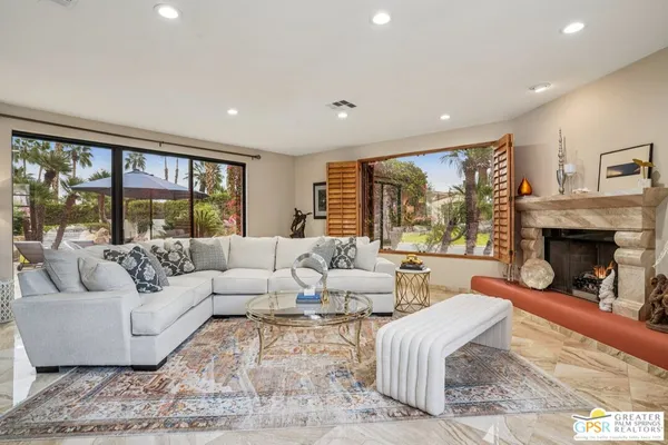 a living room with furniture large windows and a fireplace
