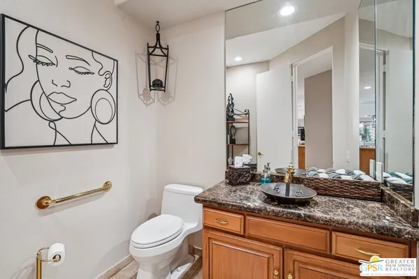 a bathroom with a granite countertop sink and a toilet