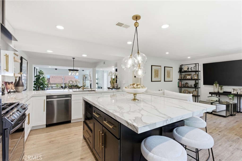 23281 Atlantis Way Dana Point, CA 92629 - Photo 21 of 81 a kitchen with a stove a sink dishwasher a kitchen island with chairs in it