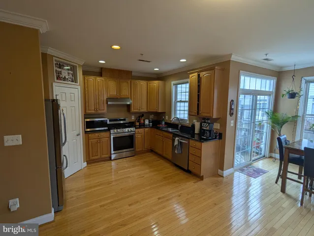 a kitchen with granite countertop wooden floors stainless steel appliances a sink and a window