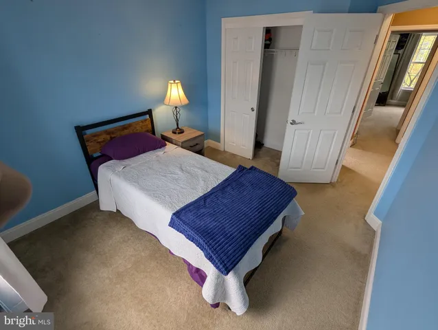 a bedroom with a bed a mirror on dresser and a window