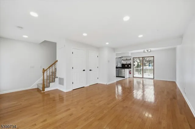 a view of an empty room with wooden floor and kitchen