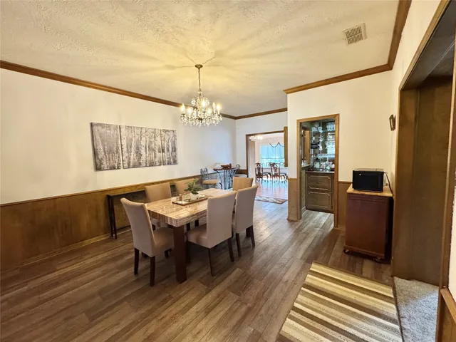 a dining room with wooden floor a chandelier a wooden table and chairs