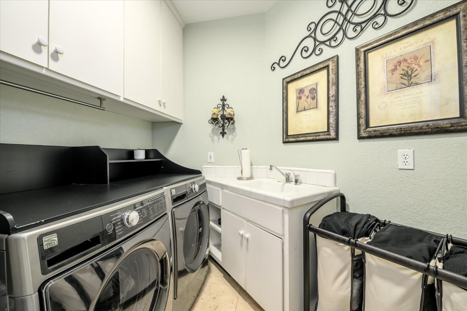 3165 Oakwood Road Cameron Park, CA 95682 - Photo 23 of 55 Laundry area is conveniently tucked away and thoughtfully designed with everything you need, including overhead cabinetry, a utility sink, and an abundance of storage space for everyday essentials.
