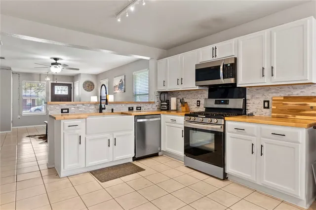 a kitchen with white cabinets appliances and a window