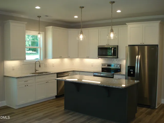 a kitchen with granite countertop a sink window and cabinets