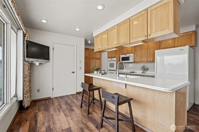 a kitchen with stainless steel appliances a sink a stove a refrigerator cabinets and a dining table with wooden floor