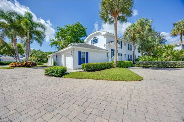 a front view of a house with a yard and potted plants