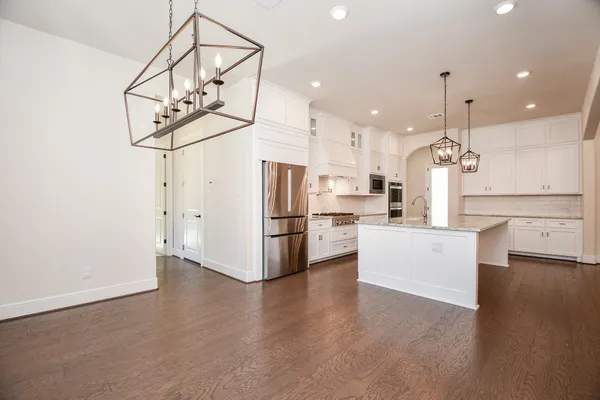 a view of a kitchen with kitchen island stainless steel appliances wooden floor and white cabinets