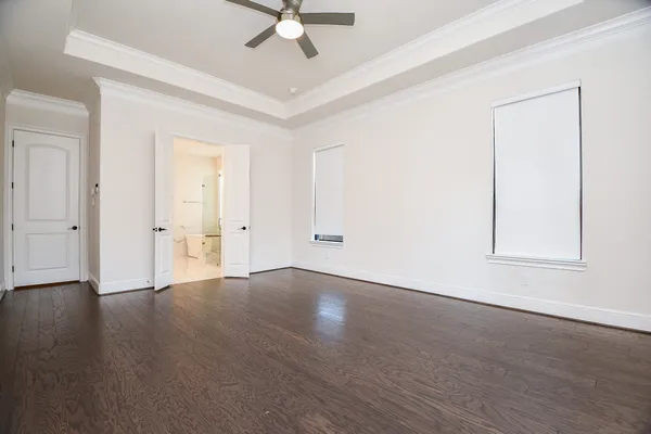an empty room with wooden floor and ceiling fan