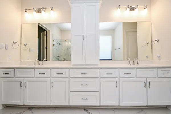 a bathroom with white cabinets and sink