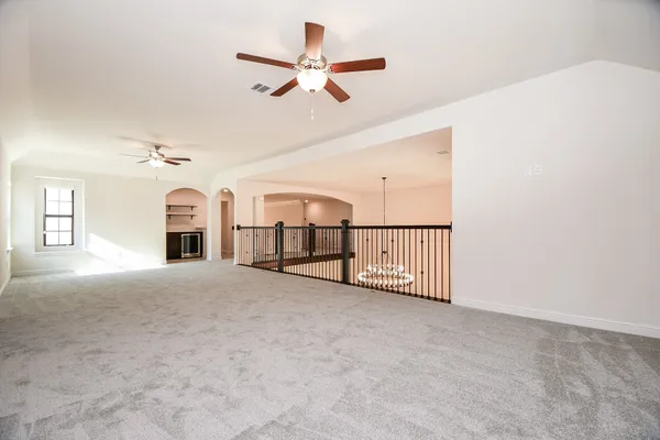 an empty room with ceiling fan and windows
