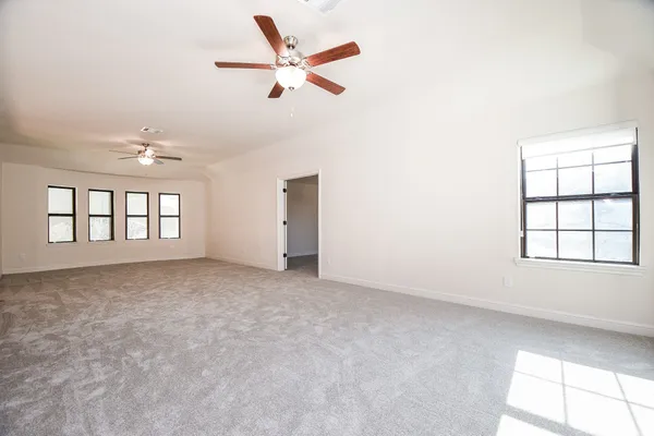 an empty room with windows and ceiling fan