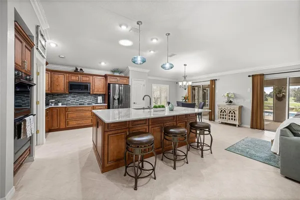 a kitchen with stainless steel appliances kitchen island granite countertop a table chairs sink and cabinets